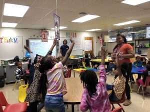 Excited students raise hands towards smiling teacher